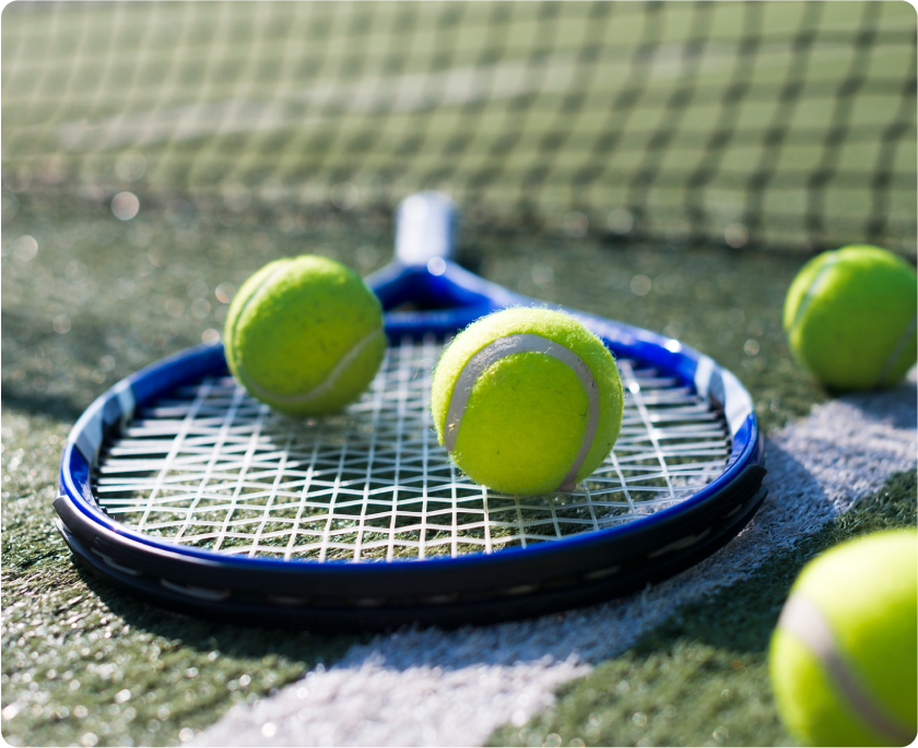 Foto de raqueta de tennis con varias pelotas verdes.